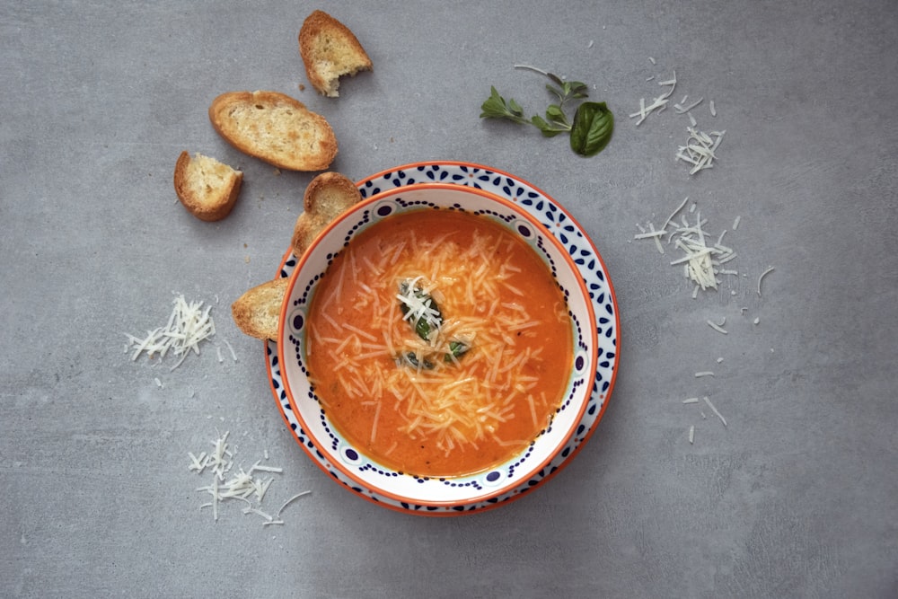 orange soup on white and blue ceramic bowl