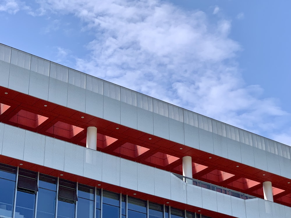 Edificio de hormigón blanco y rojo bajo el cielo azul durante el día