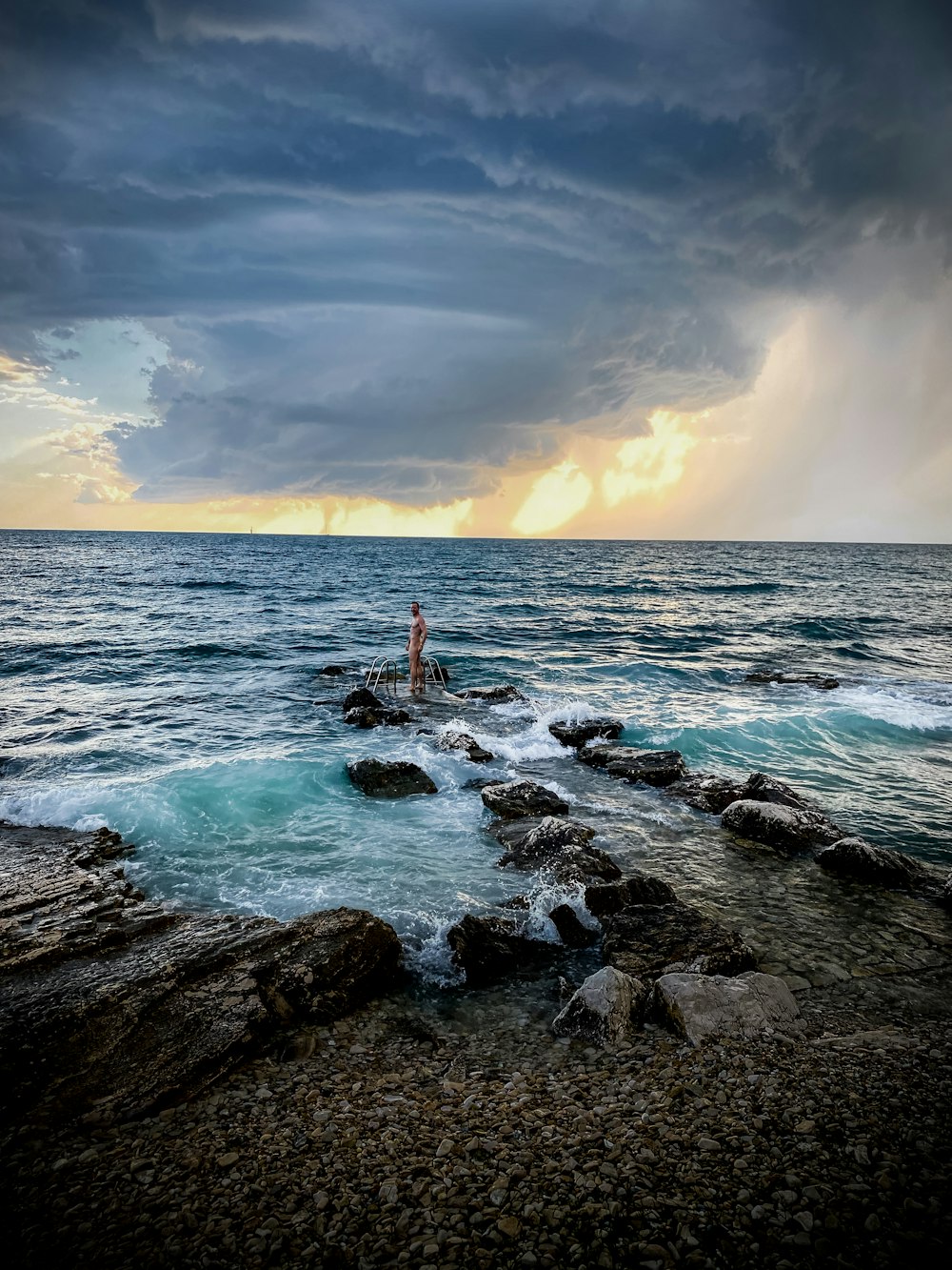 person standing on rock formation in sea during daytime