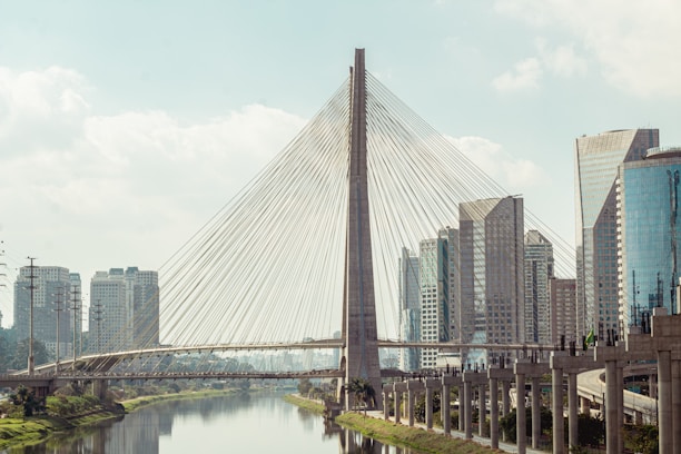 A sleek digital bridge connecting two modern cityscapes under a clear sky.