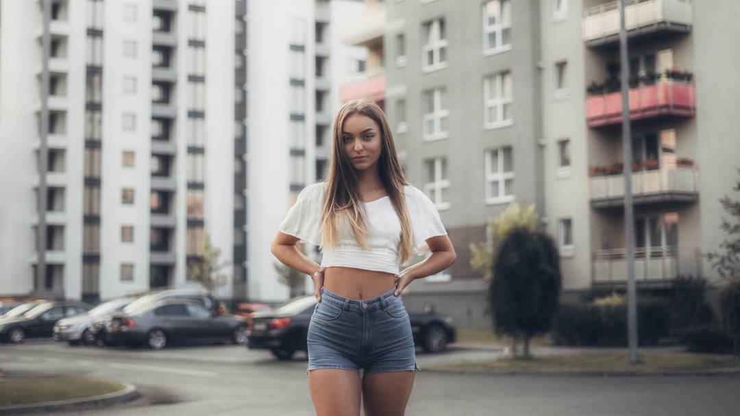 woman in white shirt and blue denim shorts standing on road during daytime