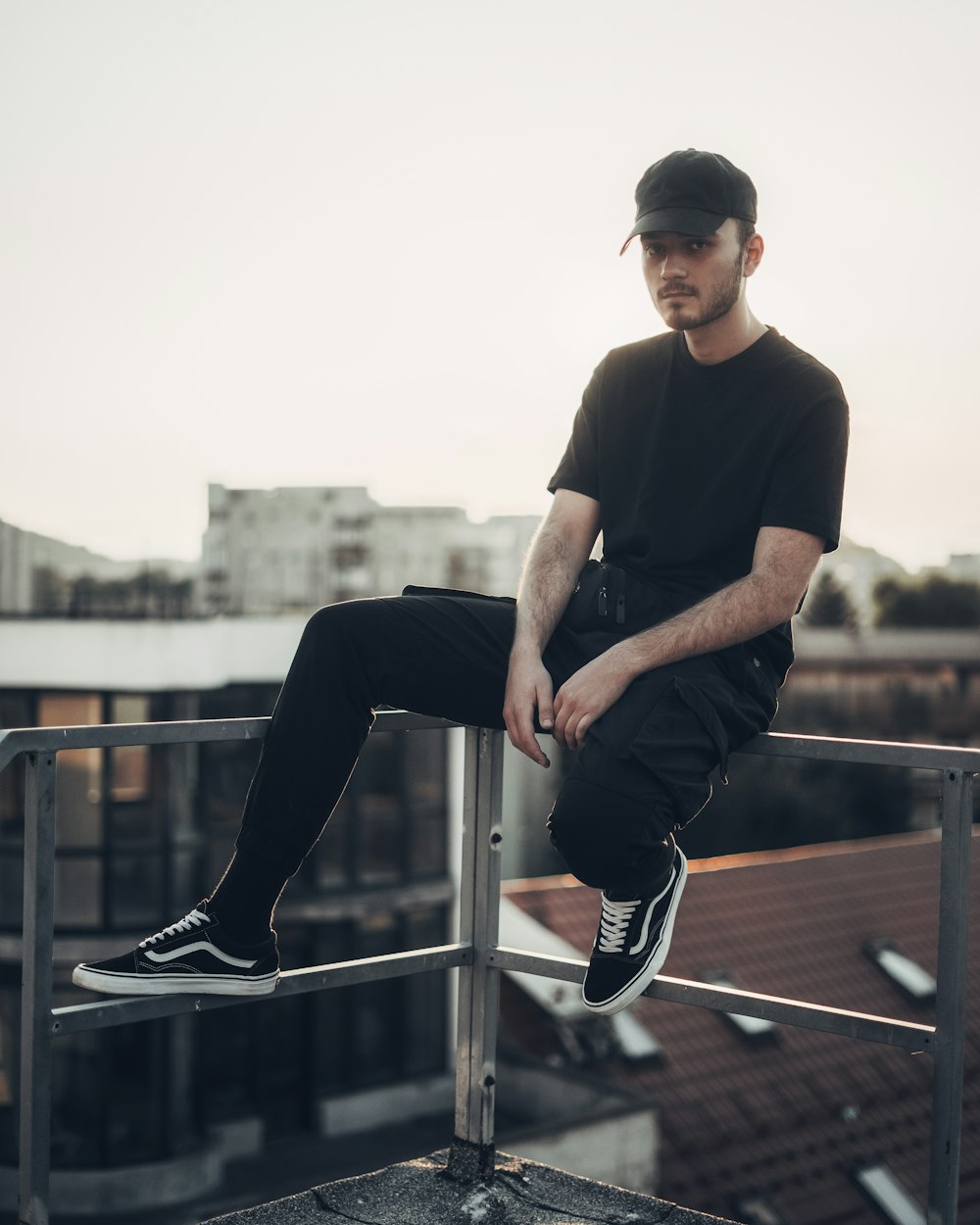 man in black crew neck t-shirt and black pants sitting on railings during daytime