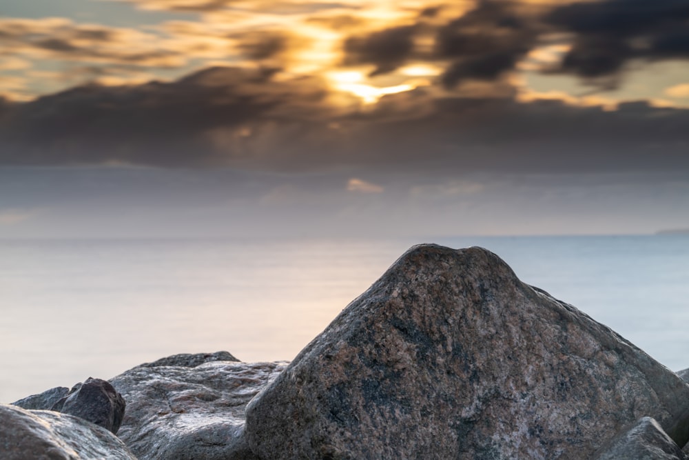 a large rock sitting on top of a beach next to the ocean