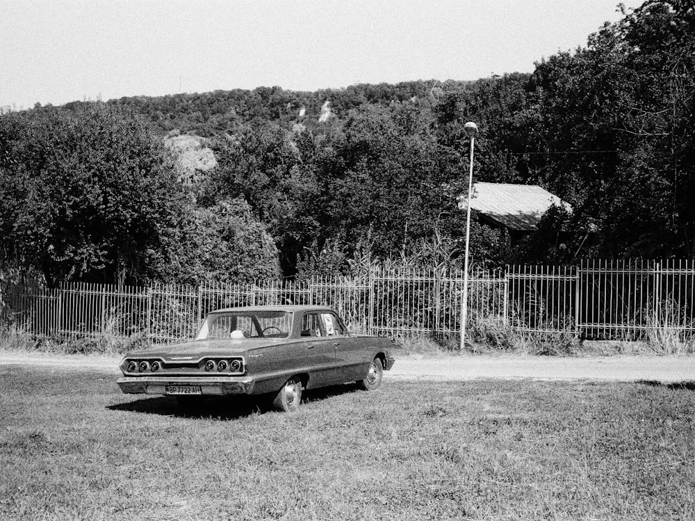 grayscale photo of classic car on grass field