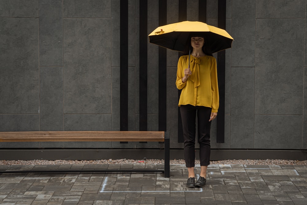 woman in yellow jacket and black pants holding umbrella
