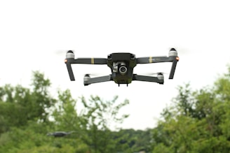 black and gray drone flying over green trees during daytime