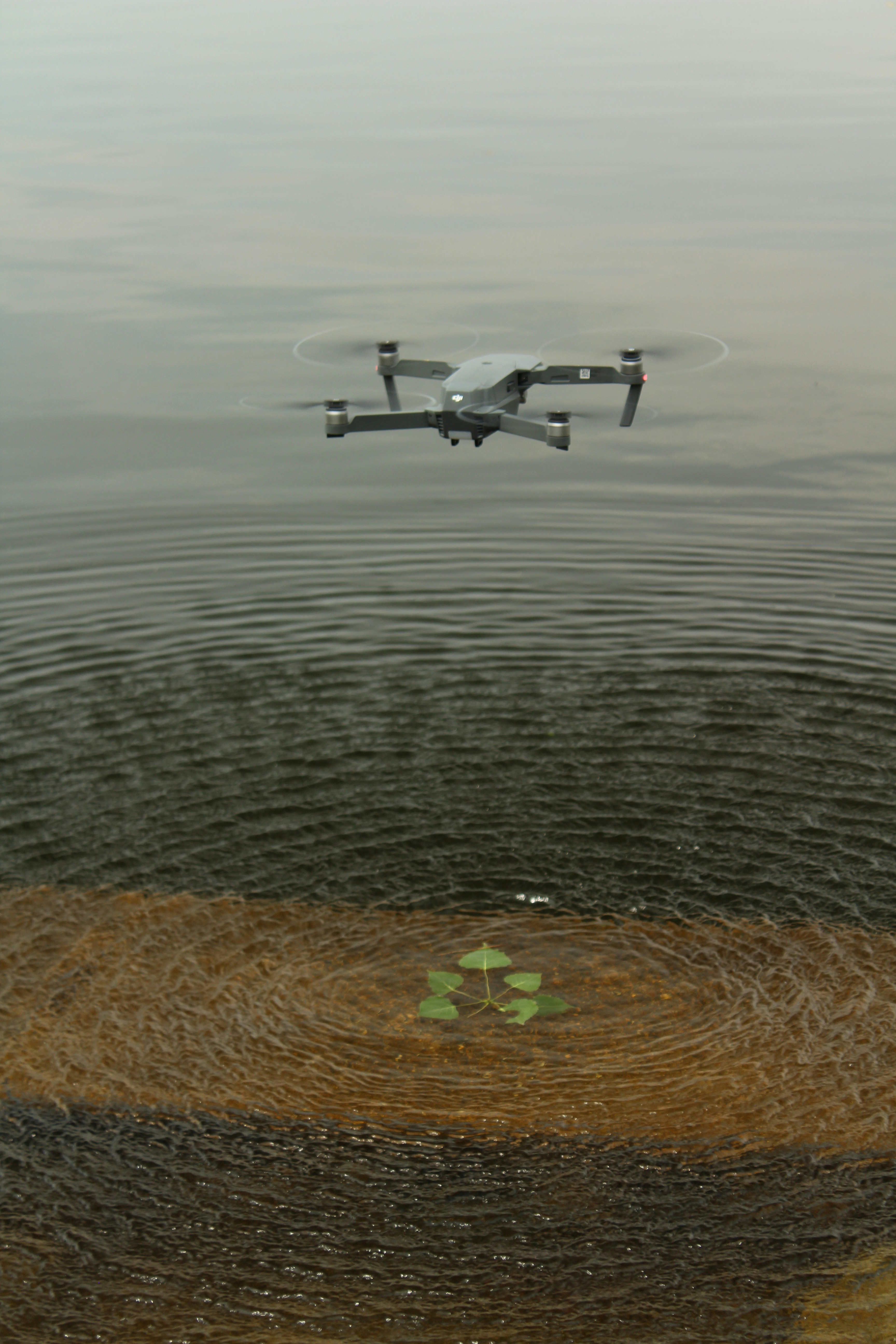 white and black drone flying over body of water during daytime
