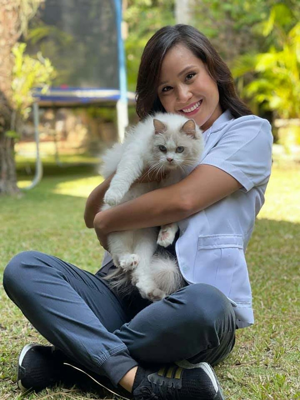 woman in blue polo shirt holding white long fur cat