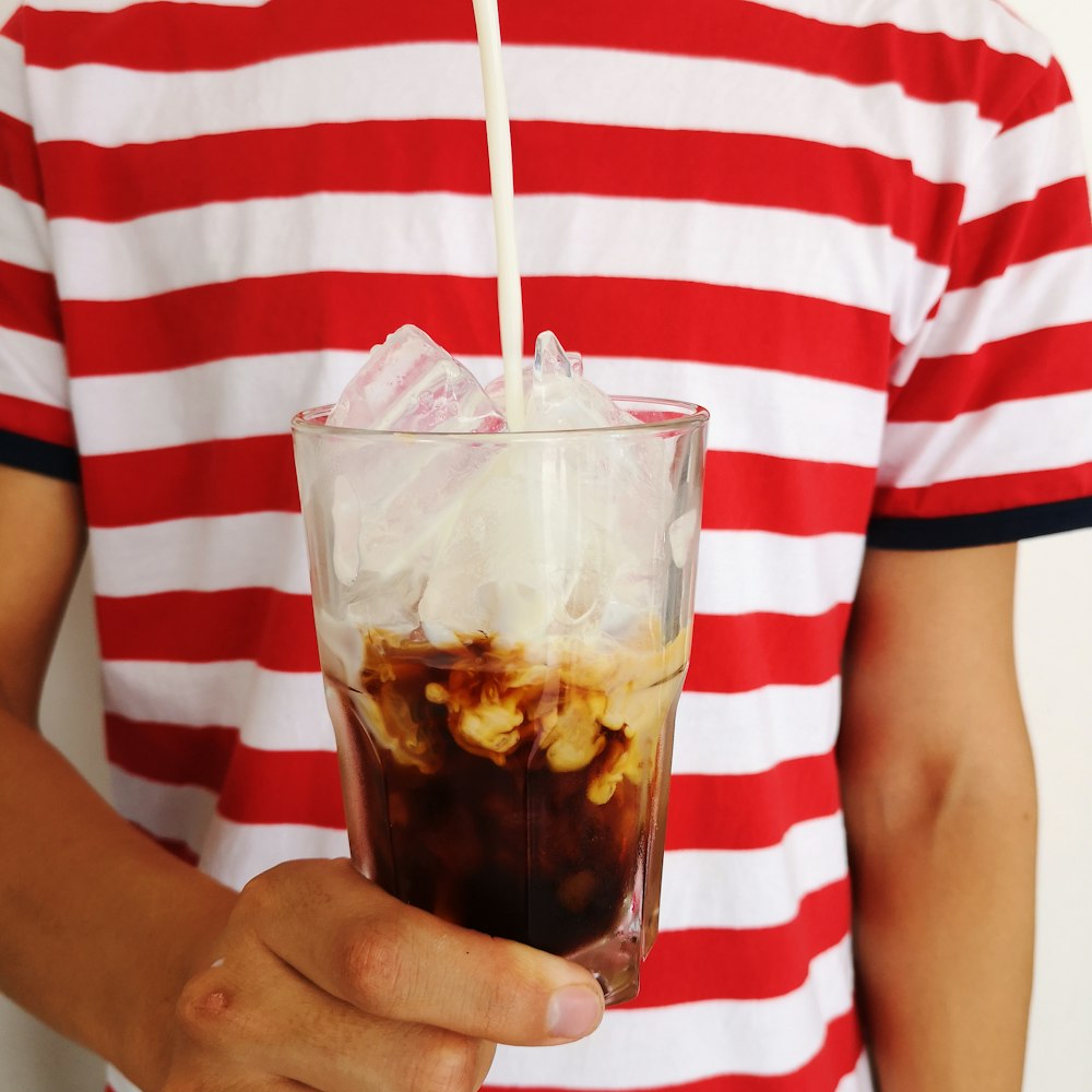 person holding clear drinking glass with ice cream