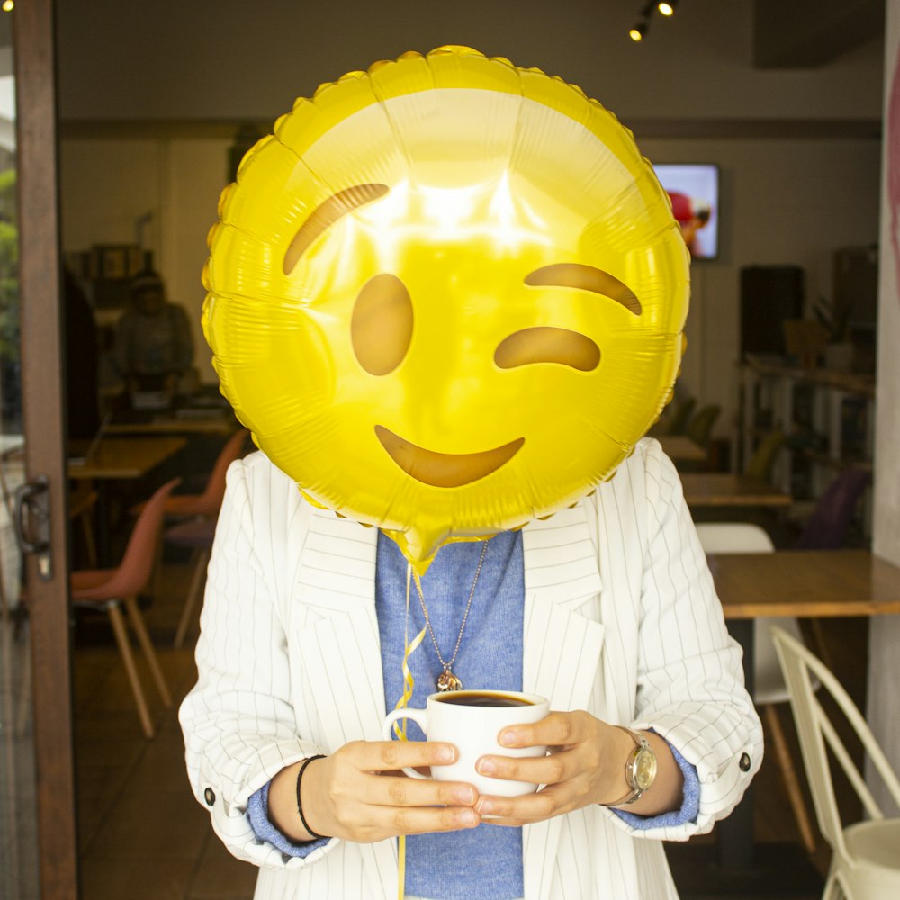 yellow emoji balloon holding blue ceramic mug