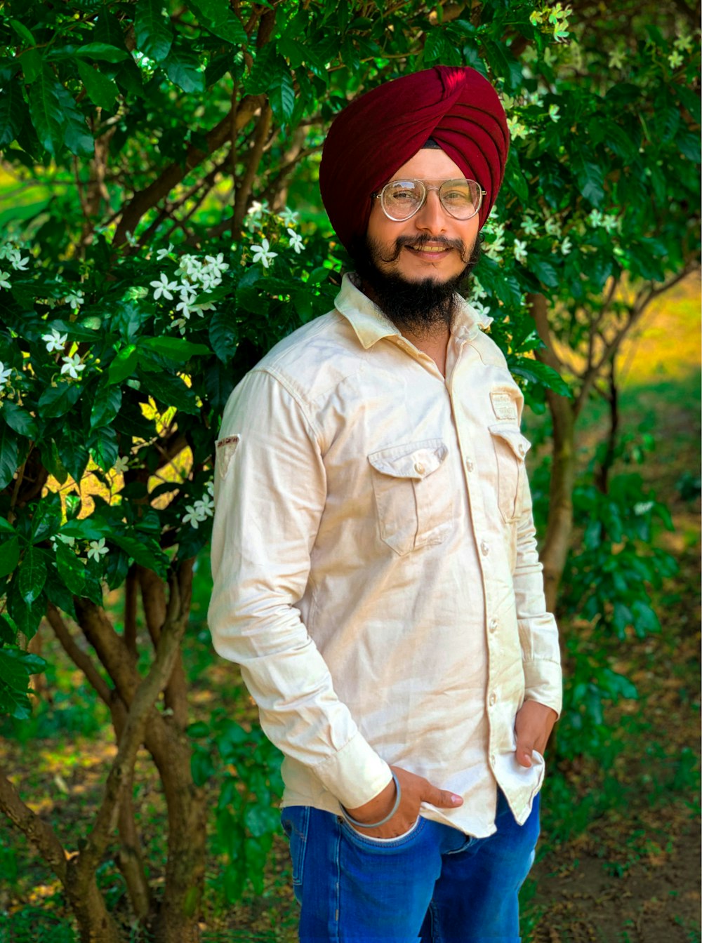 a man wearing a turban standing in front of a tree