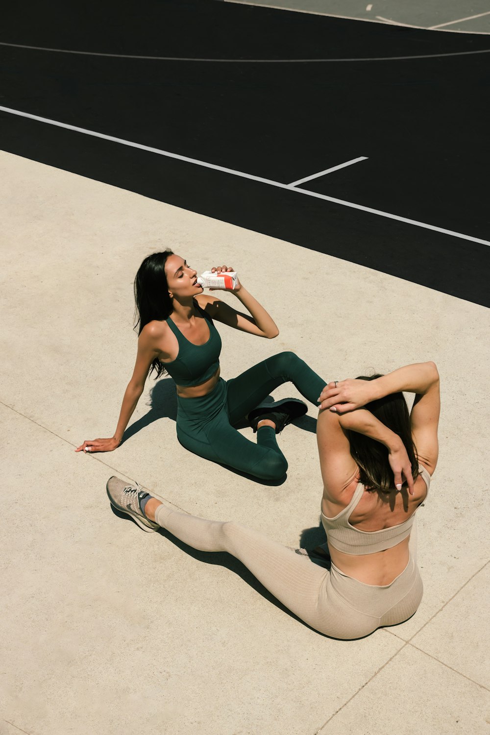 Femme en débardeur noir et short blanc assise sur un sol en béton blanc