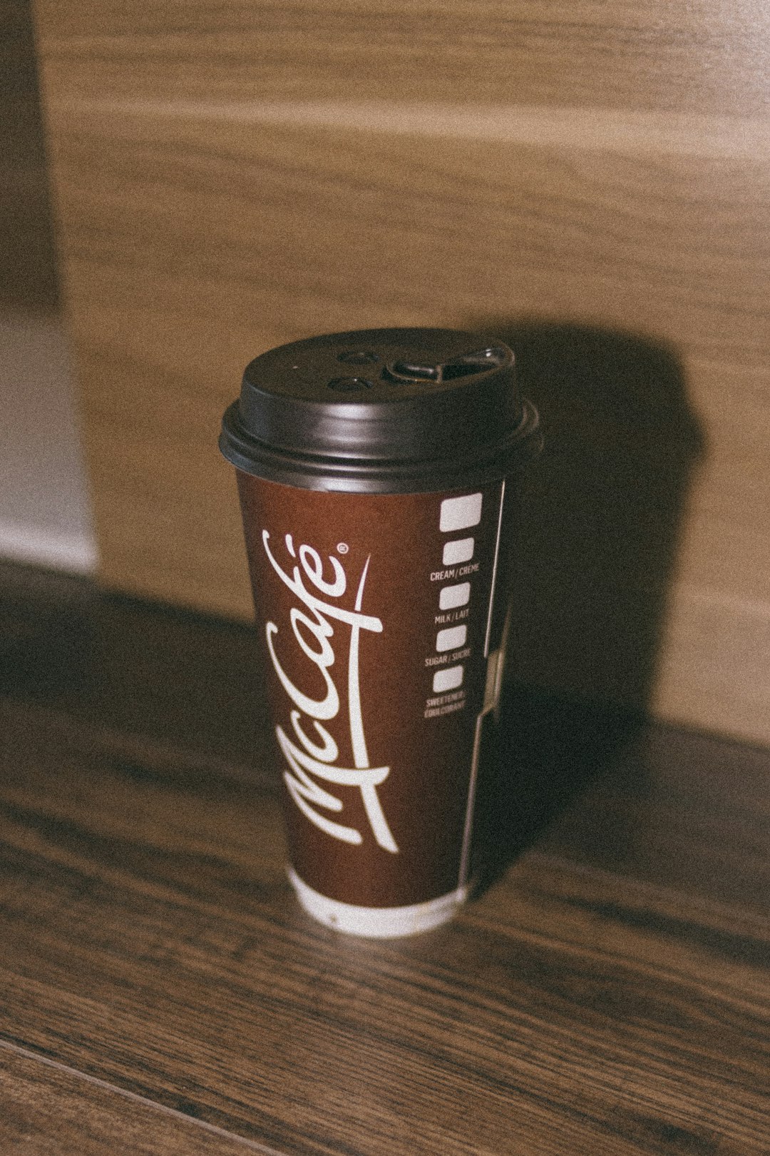 brown and black disposable cup on brown wooden table