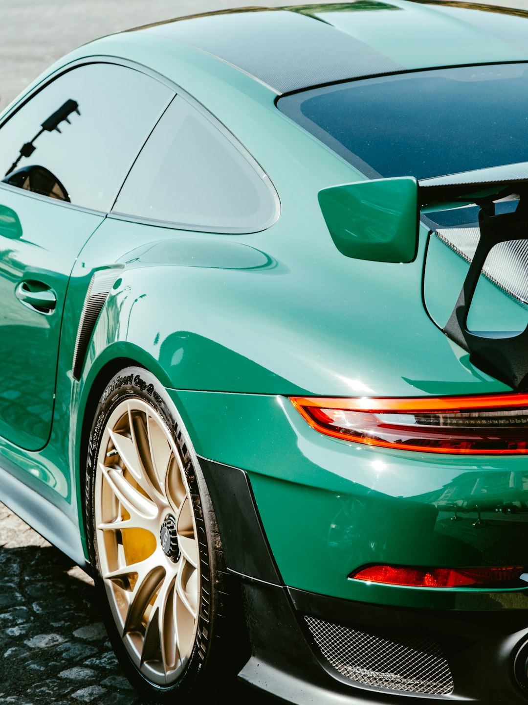 green porsche 911 parked on gray pavement