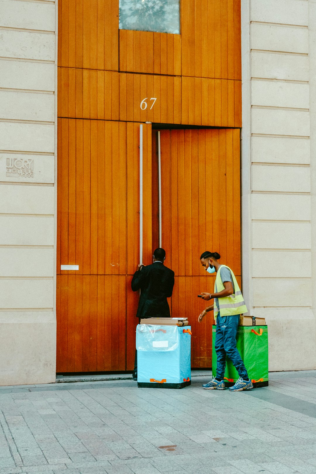 man in black jacket standing beside brown wooden door