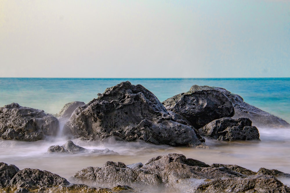 black rock formation on sea during daytime