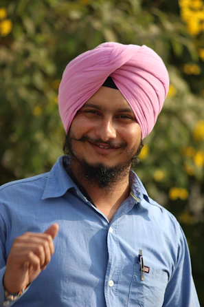 a man with a pink turban smiles at the camera