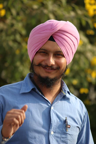 a man with a pink turban smiles at the camera