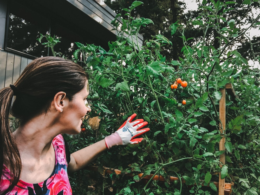 woman in purple and pink tank top holding red fruit during daytime