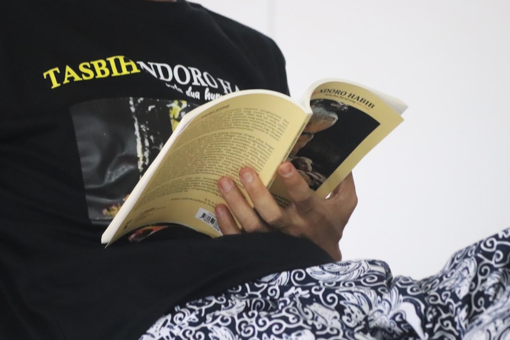 Person liest Buch über schwarz-weiße Textilien