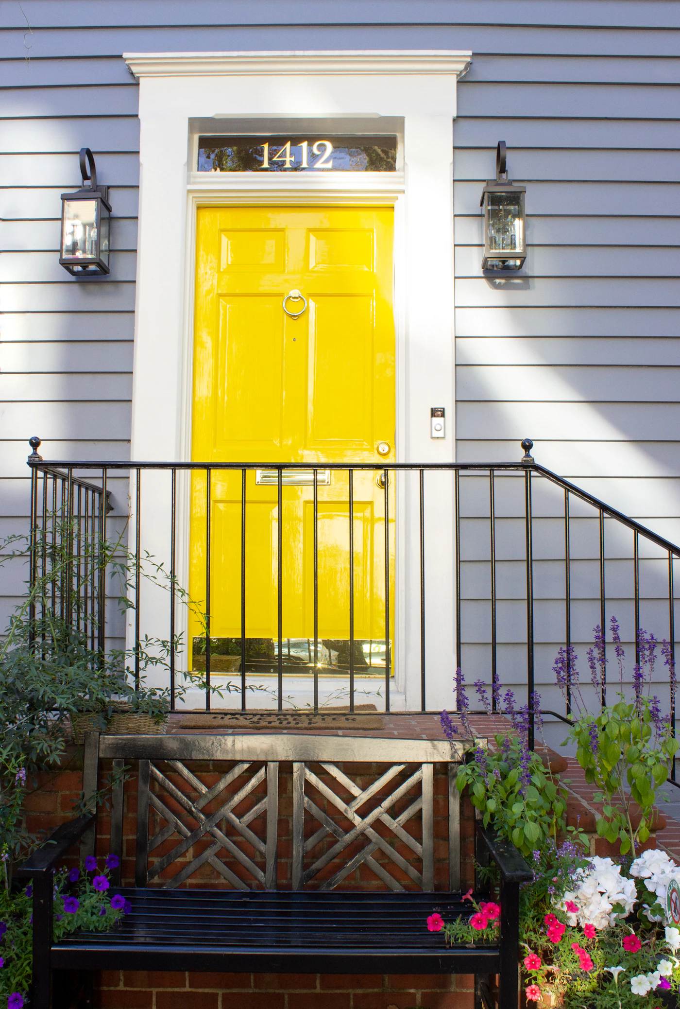Yellow front door with a black iron railing