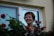 woman in red shirt standing beside red flowers