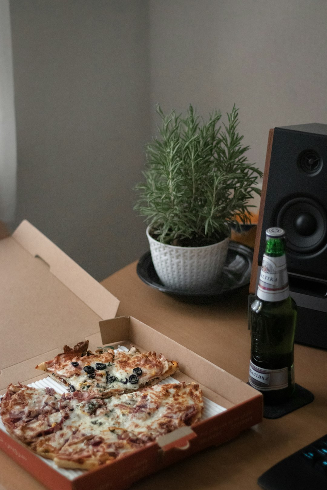 green glass bottle beside pizza on brown wooden table