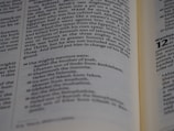 An open book displaying text that appears to be from a religious or historical document. The pages are angled, showing paragraphs of prose with section numbers and indented lists, suggesting structured content.