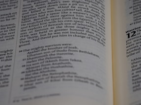 An open book displaying text that appears to be from a religious or historical document. The pages are angled, showing paragraphs of prose with section numbers and indented lists, suggesting structured content.