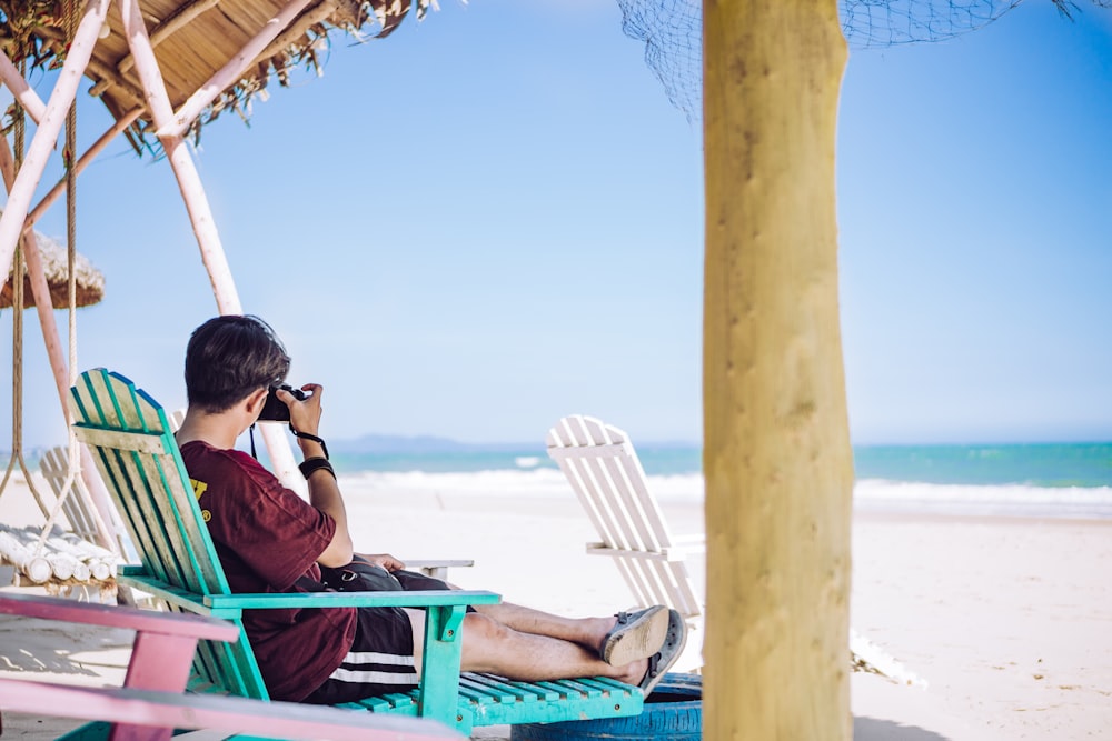 woman in green shirt sitting on green chair on beach during daytime