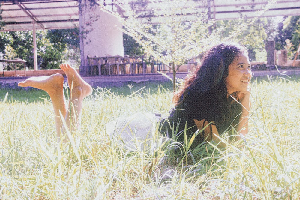 woman in black shirt lying on green grass field during daytime