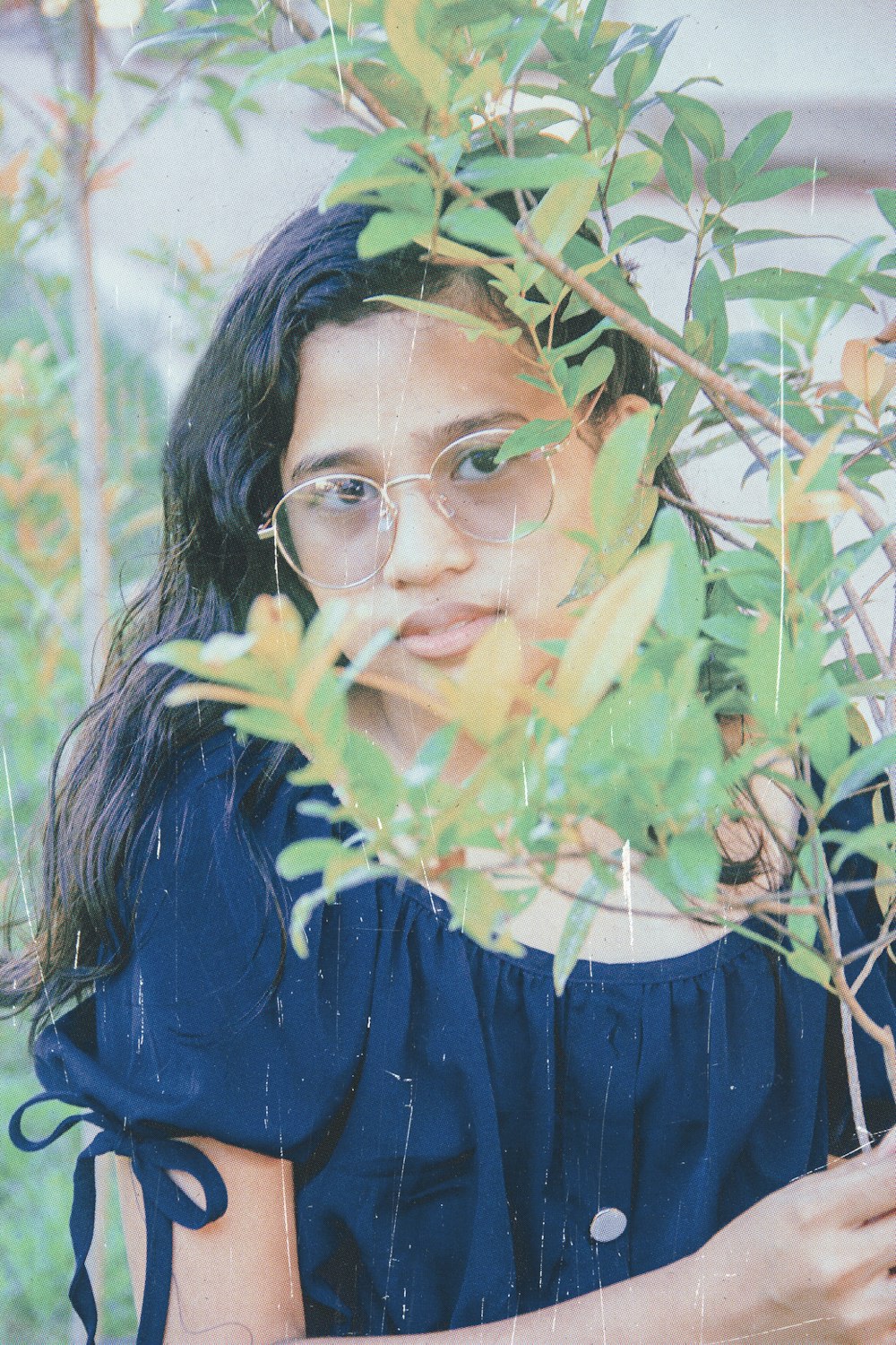 woman in blue and black shirt wearing eyeglasses with pink and green powder on her face