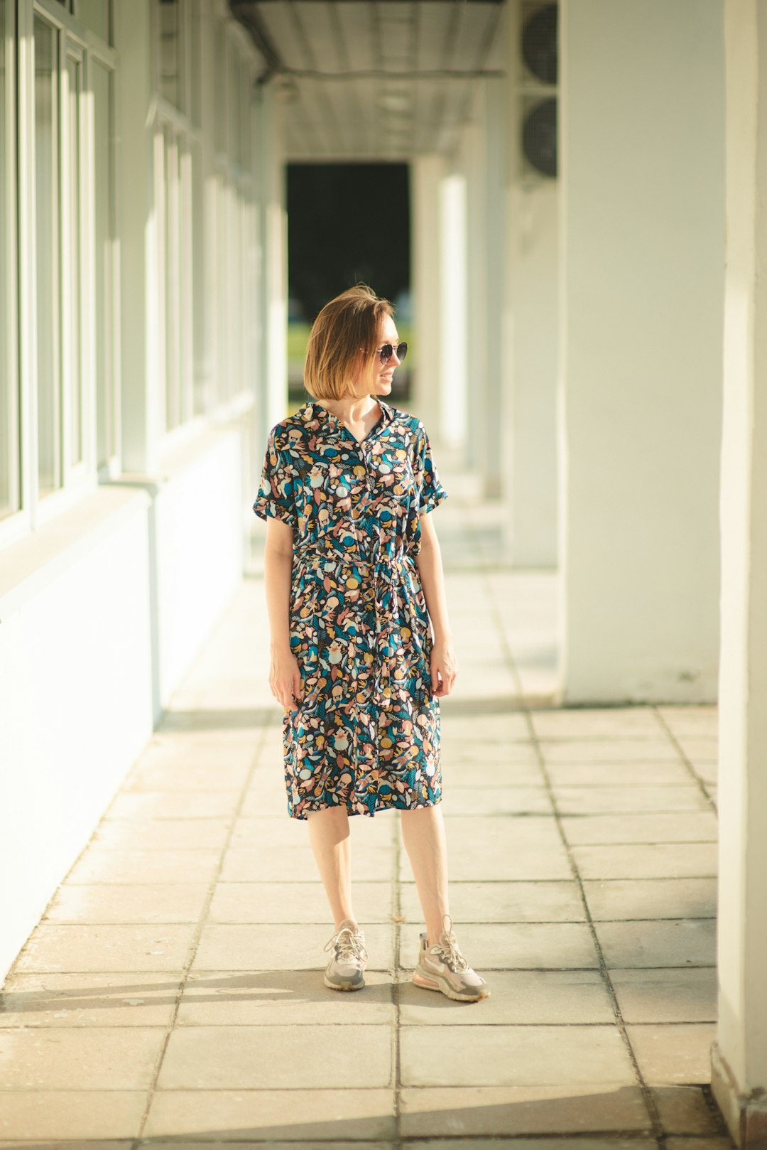 girl in blue and white floral dress standing on gray concrete floor