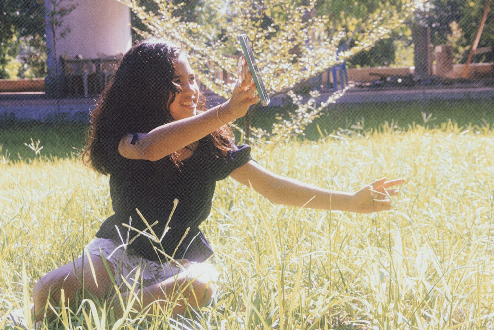 woman in black shirt and white pants sitting on green grass field