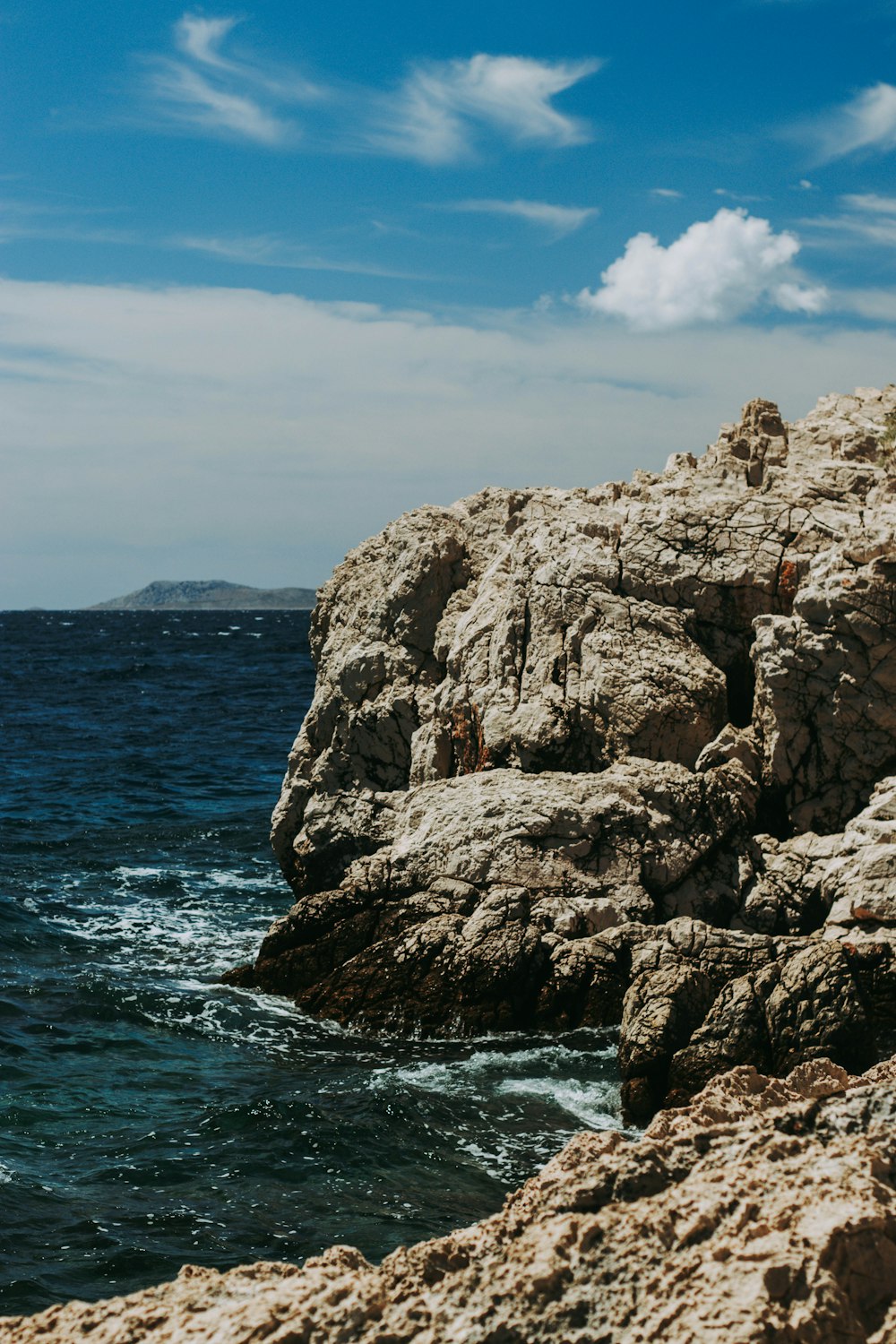 brown rock formation on sea under blue sky during daytime