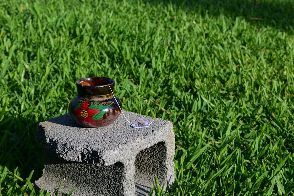 red and black ceramic vase on gray concrete stone