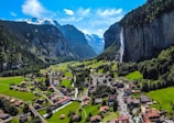 houses on green grass field near mountain under blue sky during daytime
