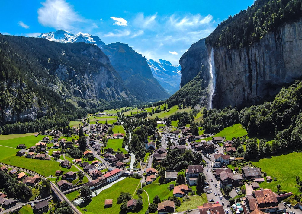 houses on green grass field near mountain under blue sky during daytime