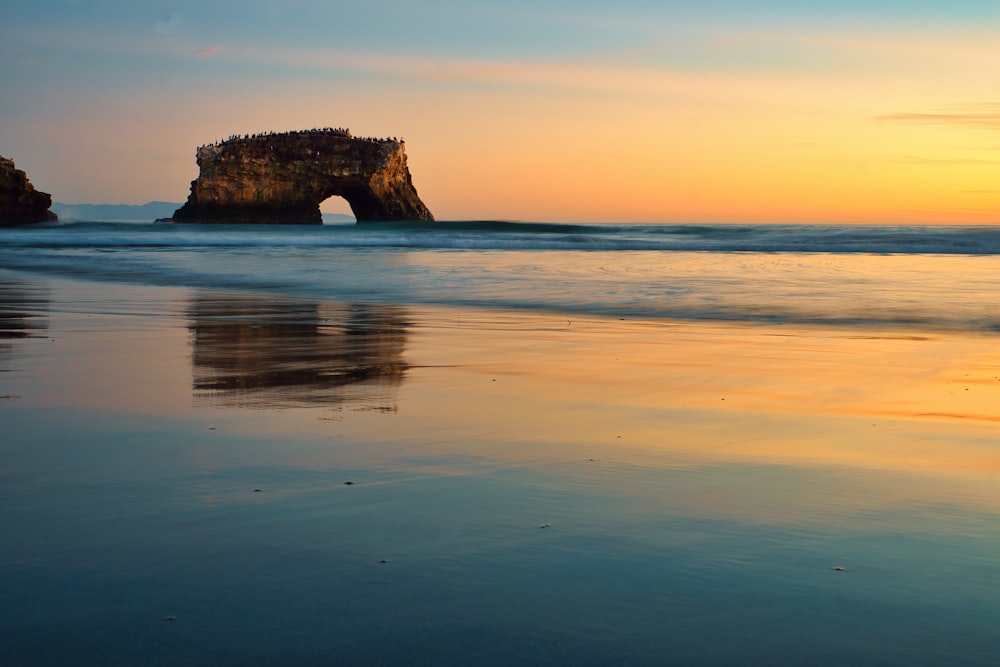 brown rock formation on sea during sunset