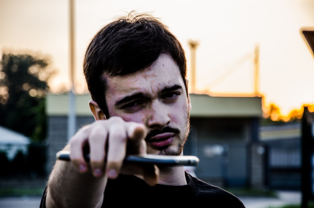 man in black crew neck shirt holding cigarette stick