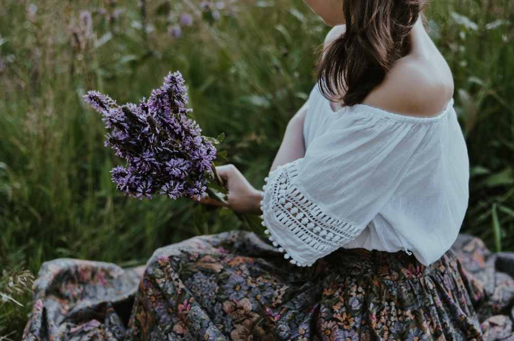 woman in white dress holding purple flowers