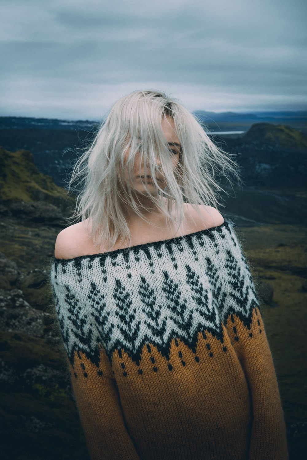 woman in brown knit sweater standing on brown field during daytime