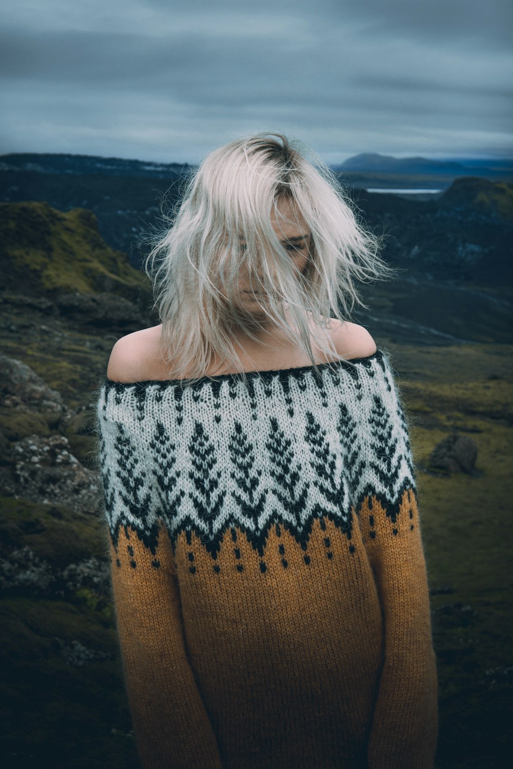 woman in brown knit sweater standing on brown rock during daytime