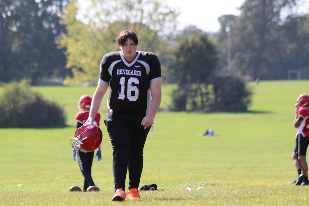 man in black and white crew neck t-shirt and black pants standing on green grass