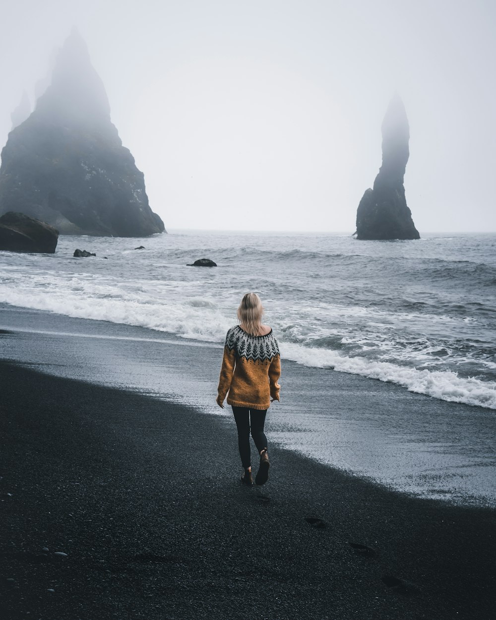 woman in yellow jacket standing on seashore during daytime