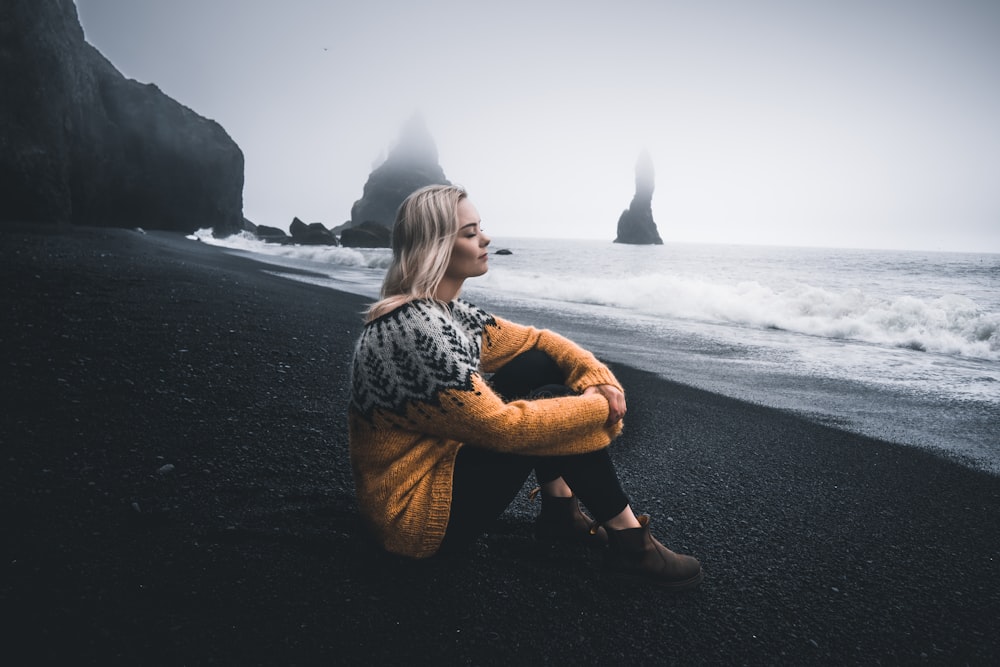 woman in black and white long sleeve shirt sitting on black sand
