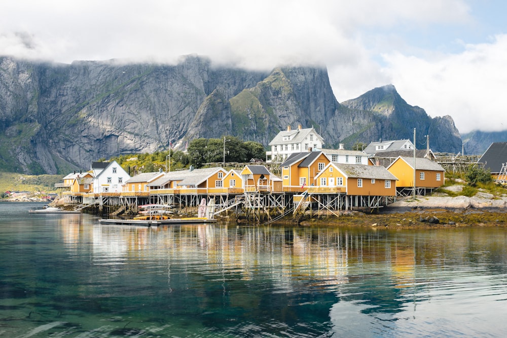 brown and white wooden houses near body of water and mountain during daytime