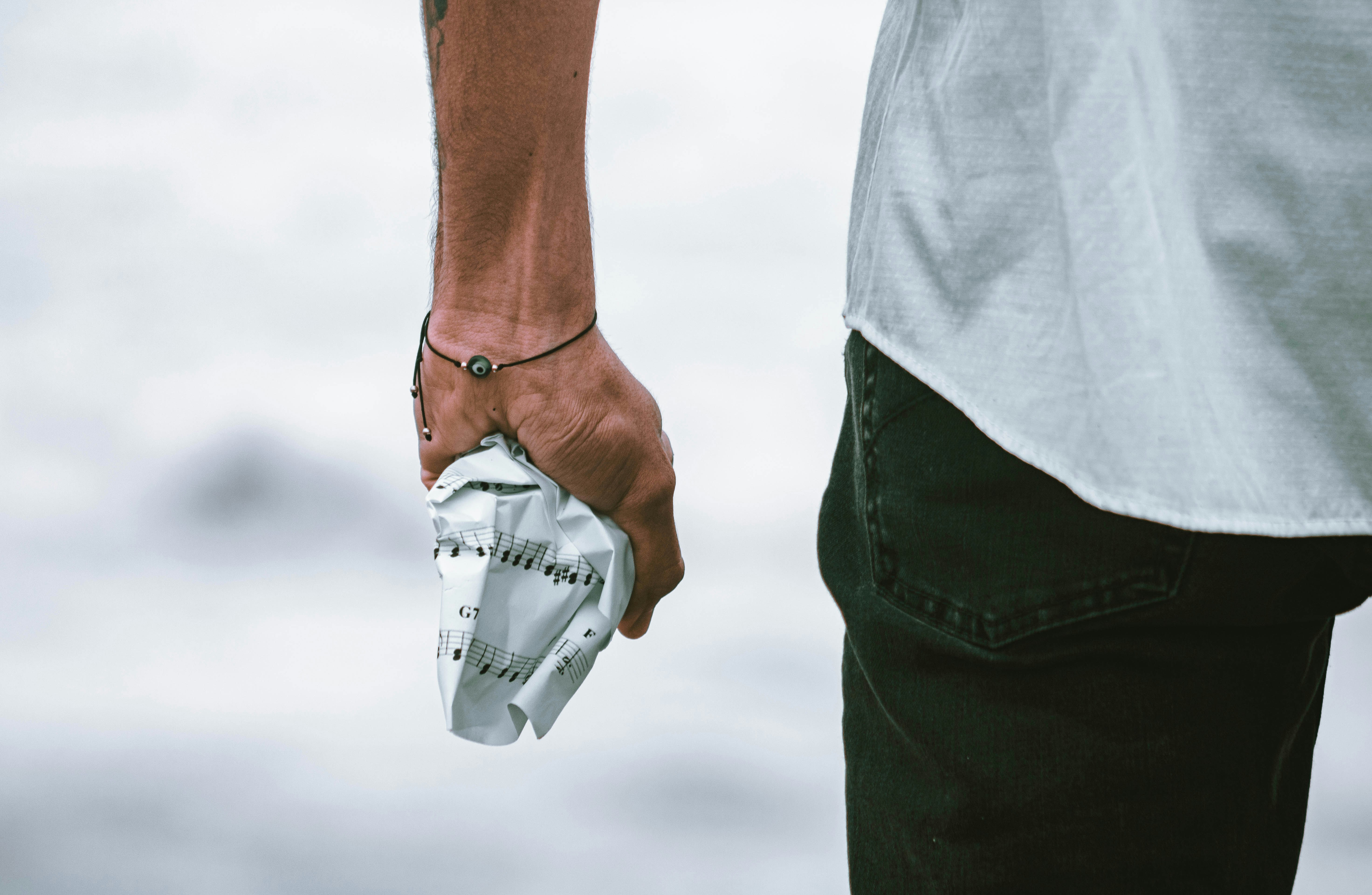 person in white shirt and blue denim jeans holding white plastic pack
