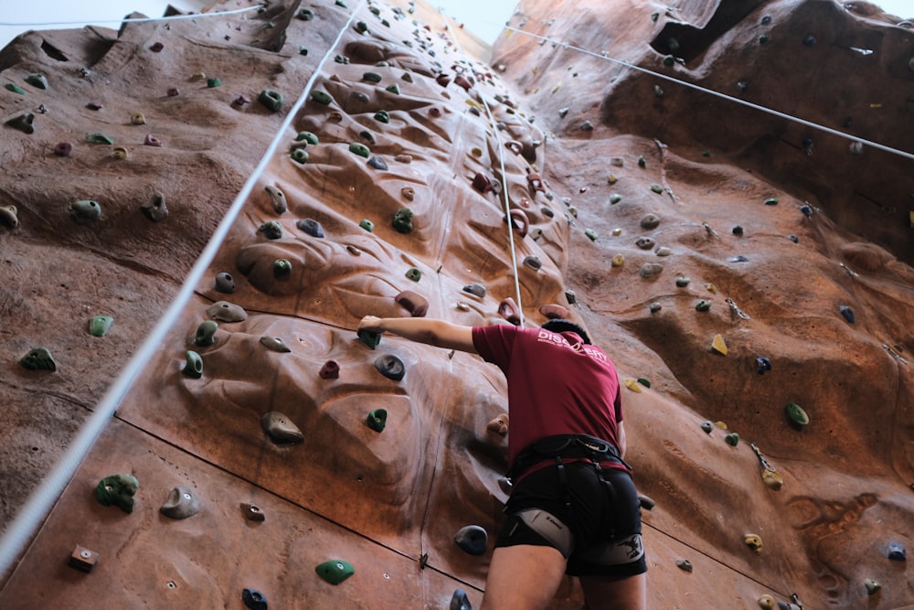 person climbing on brown rock formation during daytime