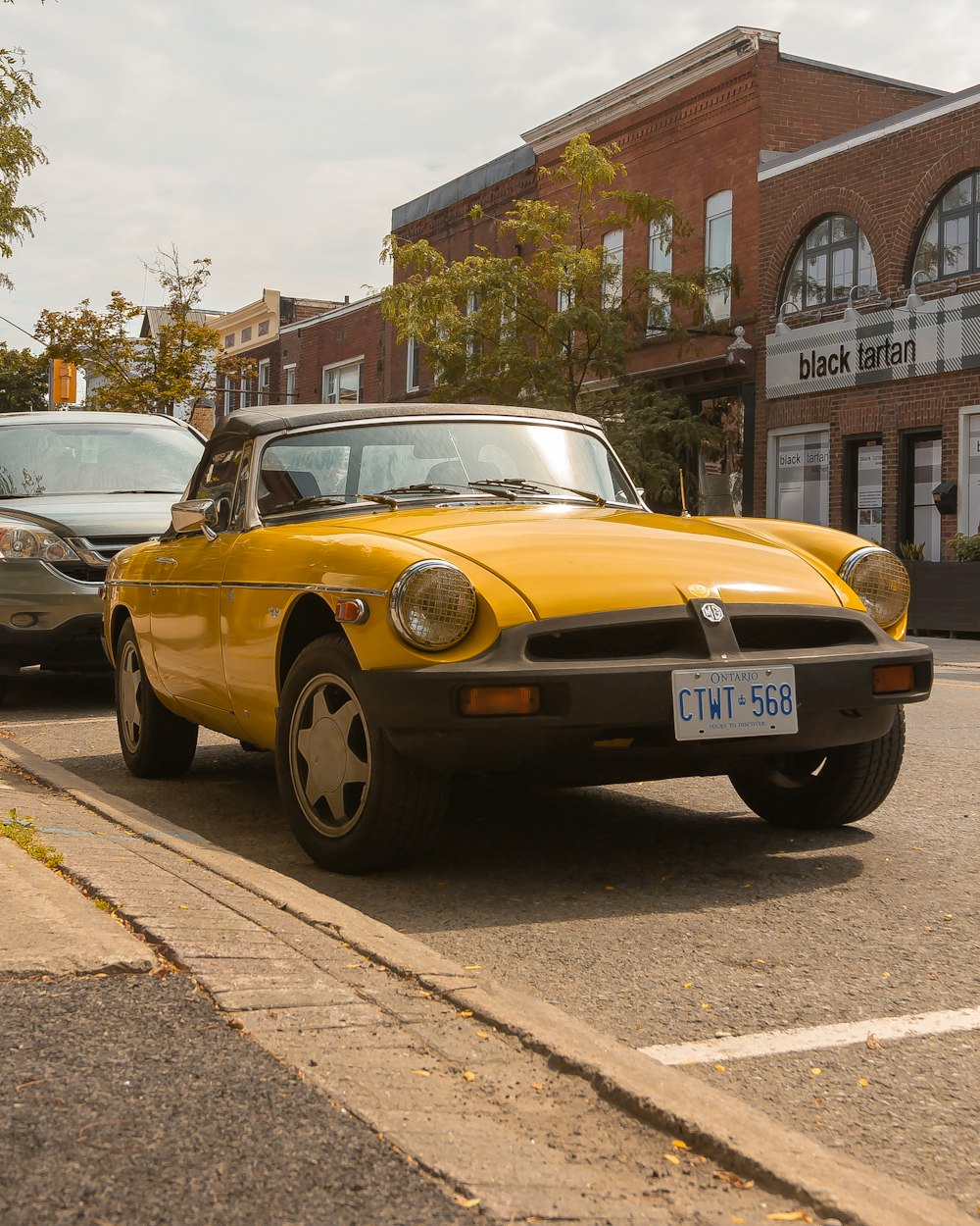 yellow and black classic car parked on sidewalk during daytime